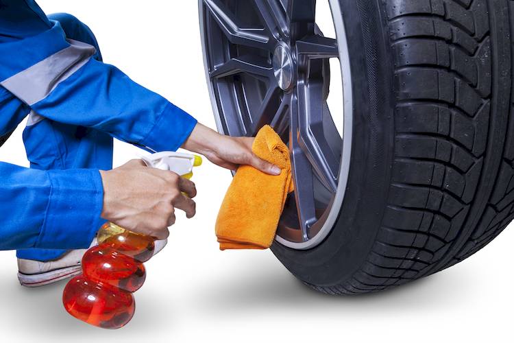 Hands cleaning off rims of car