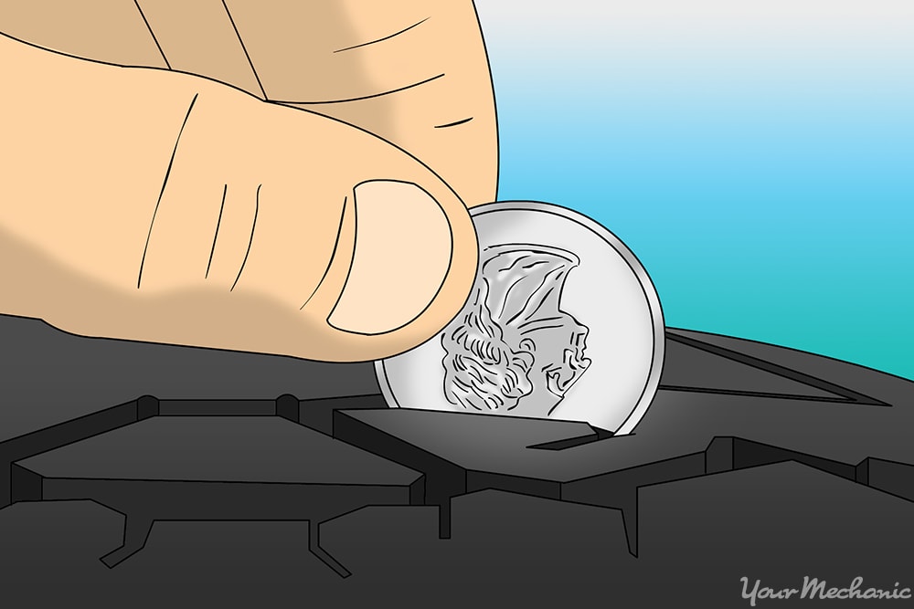 person using a quarter to check the tread on a car tire