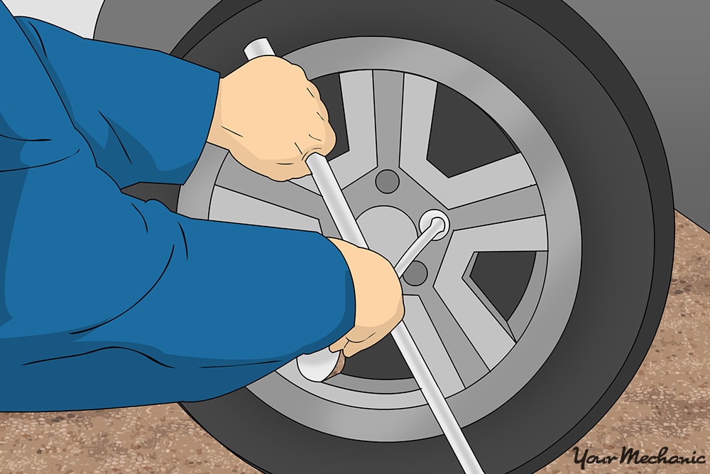 mechanic loosening lug nuts with 4-way lug wrench