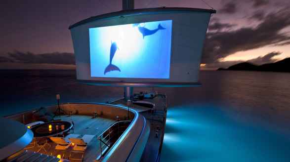 88m Maltese Falcon sailing yacht for charter - deck lit up at night with film screen