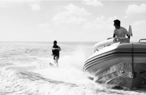 Crew member driving the tender for a guest waterskiing