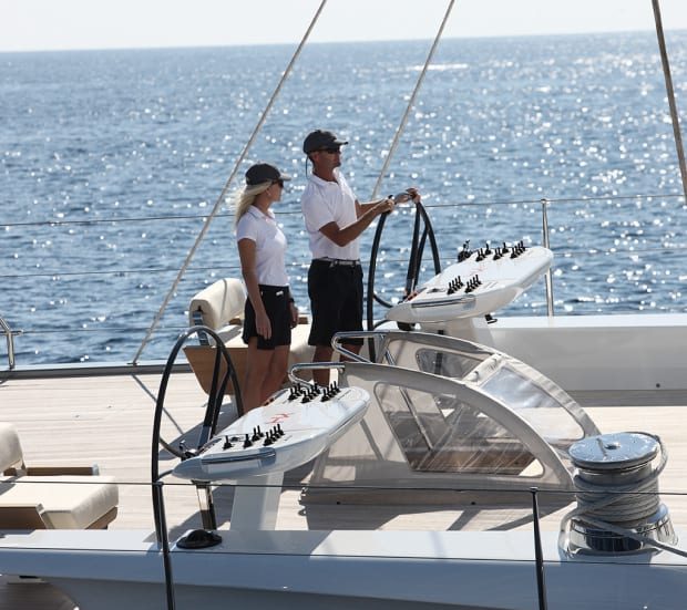 Crew steering a sailing yacht