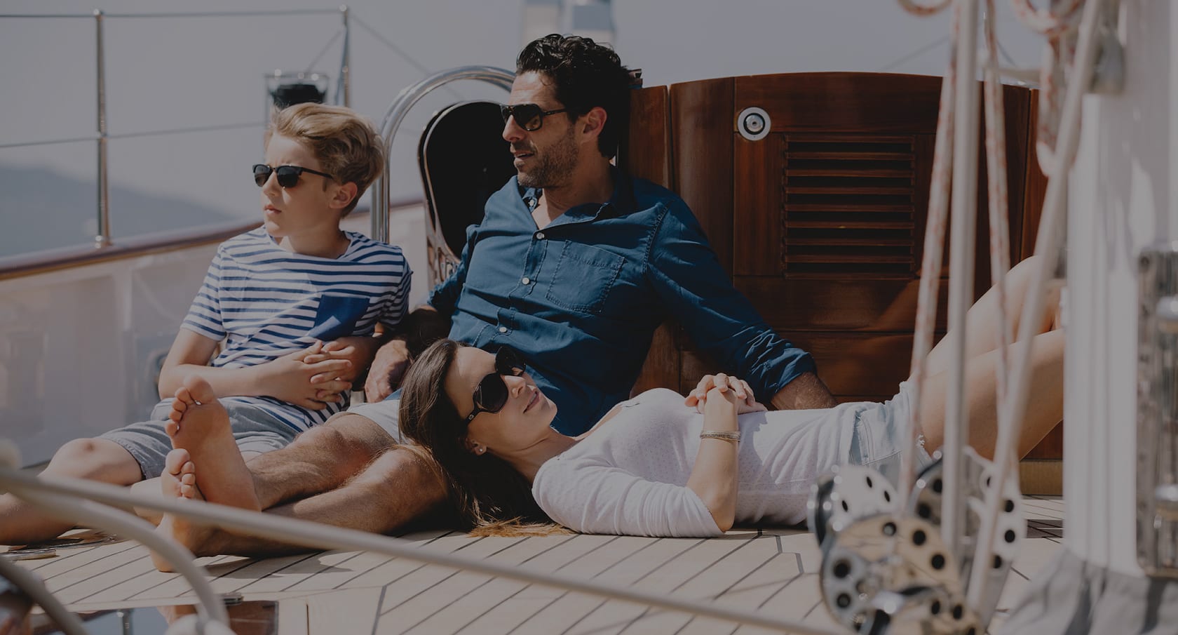 Couple and child relax on the deck of a sailing yacht