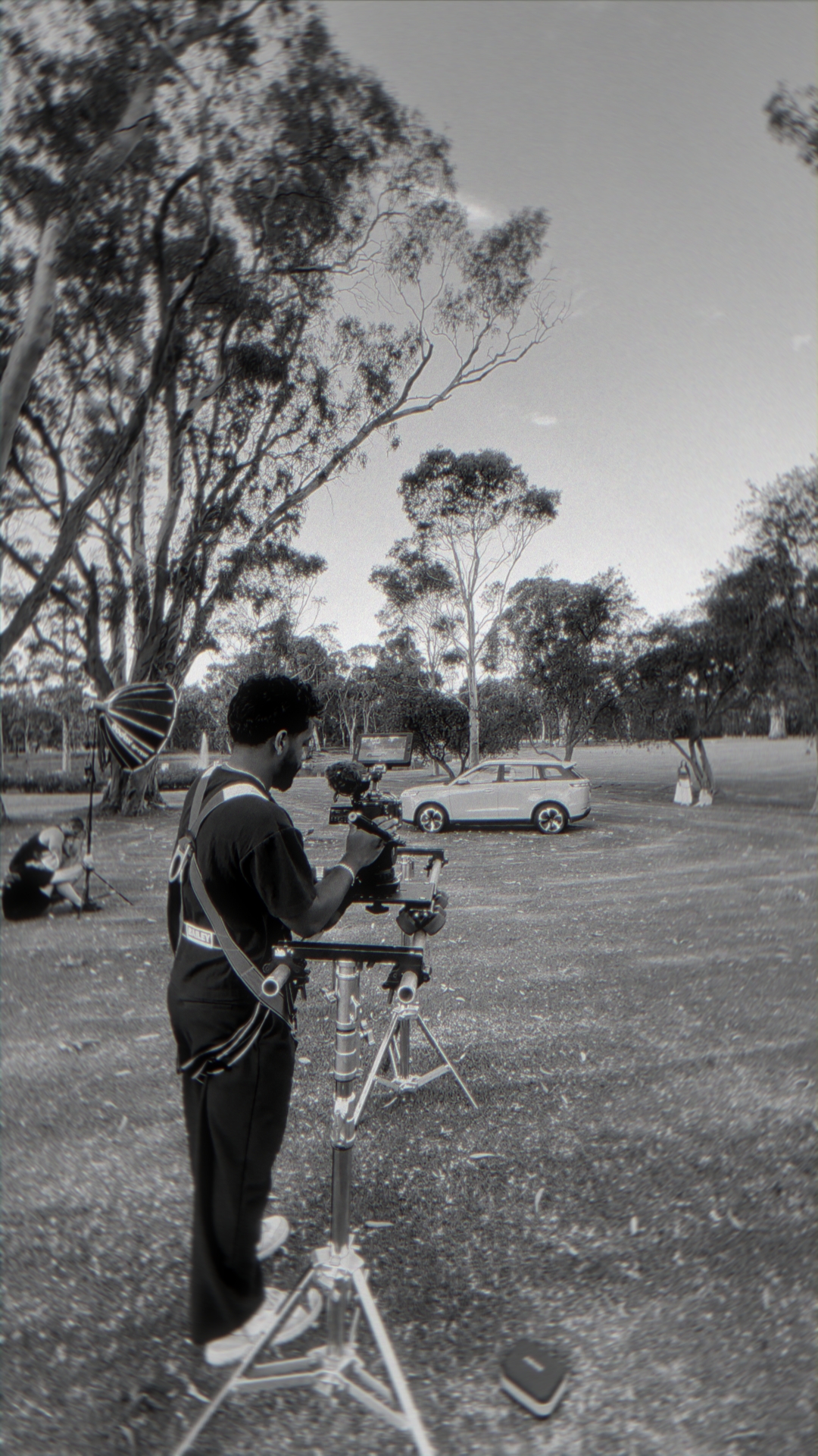 Gaffer and technician adjusting cinema lighting fixture with softbox on set