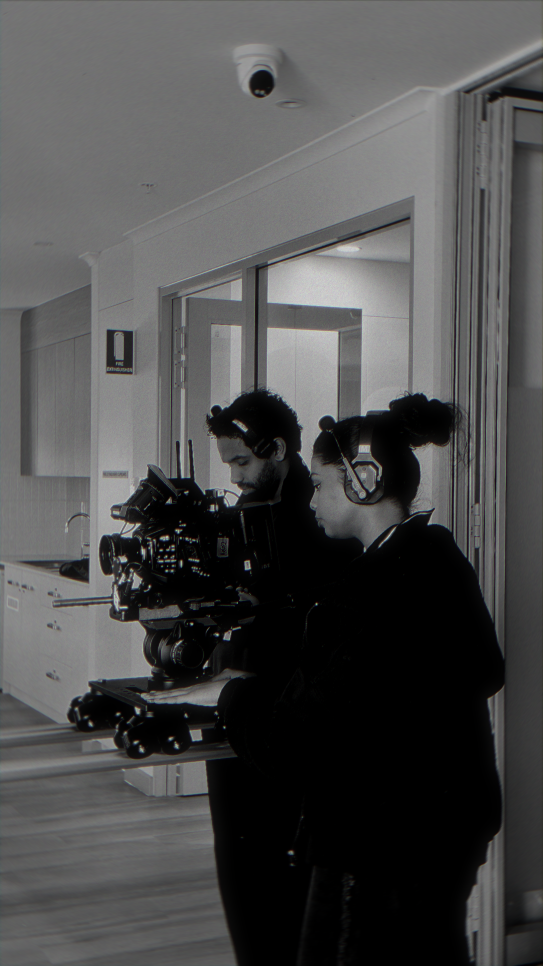 Film crew operating camera rig on set under dramatic spotlight