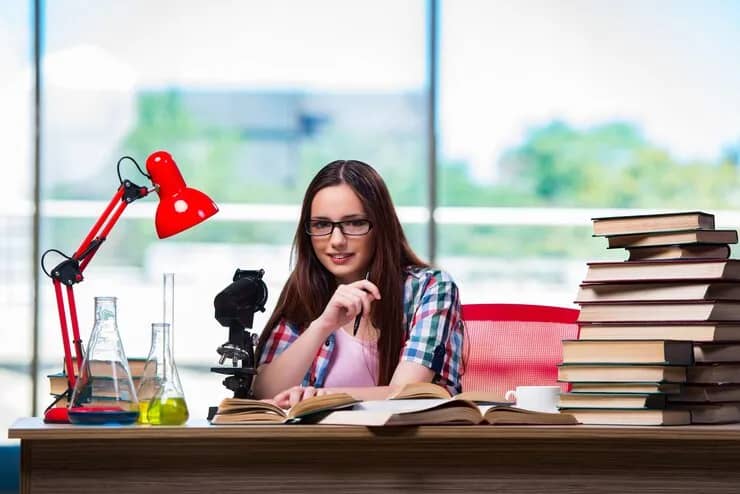 Student preparing for exams at a desk full of books