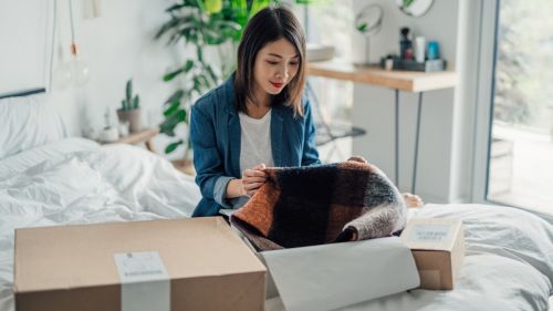 Beautiful smiling young Asian woman unpacking delivery box. Online hopping at home is efficient and convenience. Home Delivery service.