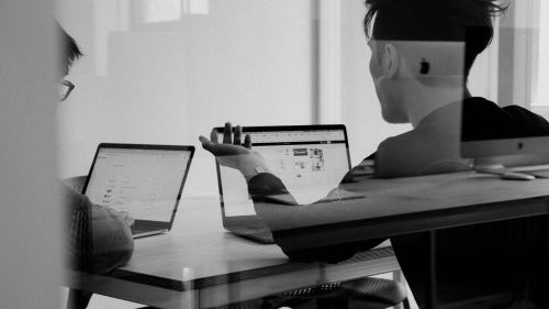 Two people talking over laptops