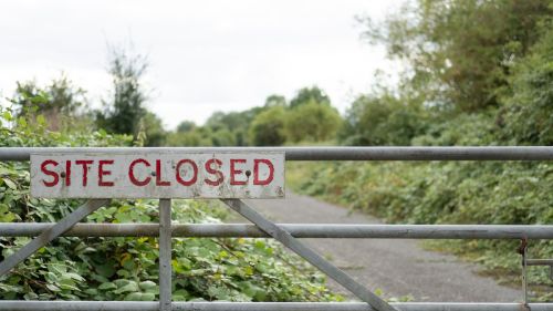 Vegetation is starting to take hold of the access road beyond the gate.