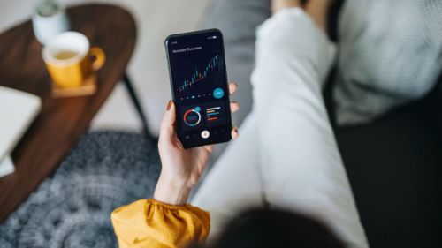 Overhead view of a woman managing finance and investment on smartphone at home.