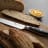 Sagenwolf Performance Bread Knife, 23cm close up on a wooden board with sliced bread 