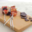 KitchenCraft Flat Sided Skewers, Set of 6 on a chopping board with figs and plums with pieces of dark chocolate on the side 