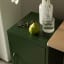 Popstrukt Sugar Cube Side Table - Dark Olive with a vase and a glass of water