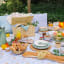 Open Oopsie-Daisy Pretty Picnics Large Picnic Blanket on the grass with a breakfast picnic selection. 