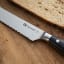 Sagenwolf Performance Bread Knife, 23cm close up blade detail on a wooden board with sliced bread  