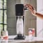 Sodastream Art Sparkling Water Maker - Black with a carbonating bottle and a glass of sparkling water