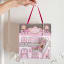 Ooh La La Artisan Confectionery The Pebbles Collection Gift Box House held next to a wall