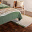 Thread Office Stripe Tassel Rug in Ivory, 160cm x 230cm next to a bed