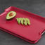 Joseph Joseph Cut and Carve Plus Chopping Board, Large - Red with avocado on the table