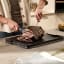 Joseph Joseph Cut and Carve Plus Chopping Board, Large - Black on the table slicing steak
