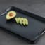 Joseph Joseph Cut and Carve Plus Chopping Board, Large - Black with an avocado on the table