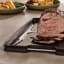 Joseph Joseph Cut and Carve Plus Chopping Board, Large - Black on the table with sliced steak