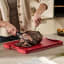 Joseph Joseph Cut and Carve Plus Chopping Board, Large - Red on the table slicing some steak