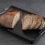 Joseph Joseph Cut and Carve Plus Chopping Board, Extra Large - Black with sliced bread on. the kitchen counter