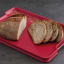 Joseph Joseph Cut and Carve Plus Chopping Board, Extra Large - Red with sliced bread on the table
