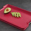 Joseph Joseph Cut and Carve Plus Chopping Board, Extra Large - Red with an avocado on the table