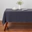 Maxwell & Williams Cotton Classics Rectangular Tablecloth, 2.3m - Slate on the table with a dinner set and a flower pot