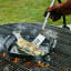 Le Creuset Outdoor Stainless Steel Slotted Turner Spatula turning fish in a grilling basket