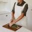 Me Thyme Cross-Over Apron - Light Oatmeal worn in the kitchen