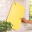 Zuutii Double-Sided Chopping Board - Light Lemon hanging on a hook