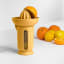 Blim Plus UFO Juicer with QB Jug - Desert Dark on the table  with oranges