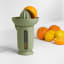 Blim Plus UFO Juicer with QB Jug - Forest Dark on the table with oranges