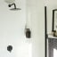 Joon Matte Black Adjustable Dispenser with Amber Bottle - Double on a wall in the shower