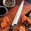 Tramontina Yanagiba Gold Sushi Knife, 23cm on a chopping board