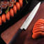 Tramontina Yanagiba Silver Sushi Knife, 23cm on a chopping board