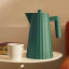 Alessi Plisse Electric Kettle, 1.7L - Green on a table with a cup of tea