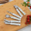 Laura Ashley Stainless Steel Garlic Press with Ceramic Handle - Sage Parterre on a chopping board