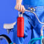 Le Creuset On The Go Vacuum-Insulated Stainless Steel Bottle, 500ml - Cerise handheld with a bicycle 