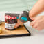 Dreamfarm Dopener 3-in-1 Ergonomic Can Opener opening a can on a chopping board