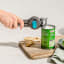 Dreamfarm Dopener 3-in-1 Ergonomic Can Opener opening a can on a chopping board