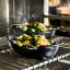 Le Creuset Gourmet Matte Black Collection Cast Iron Mini Oval Bakers, Set of 4 with food on a rack