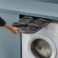Joseph Joseph Hold-All Max Grey Collapsible Laundry Basket, 55L stored between the washing machine and shelf