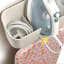 Joseph Joseph IronHub Wall-Mounted Ecru Iron Storage Caddy detail with an iron and ironing board