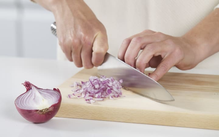 Cutting onion on wooden board 