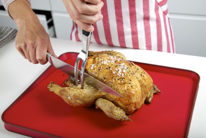 Cutting chicken on plastic board 
