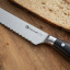 Sagenwolf Performance Bread Knife, 23cm close up blade detail on a wooden board with sliced bread  